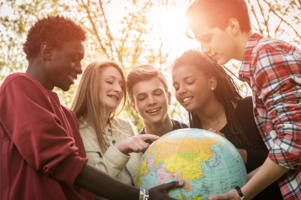 middle schoolers and teens standing around a globe