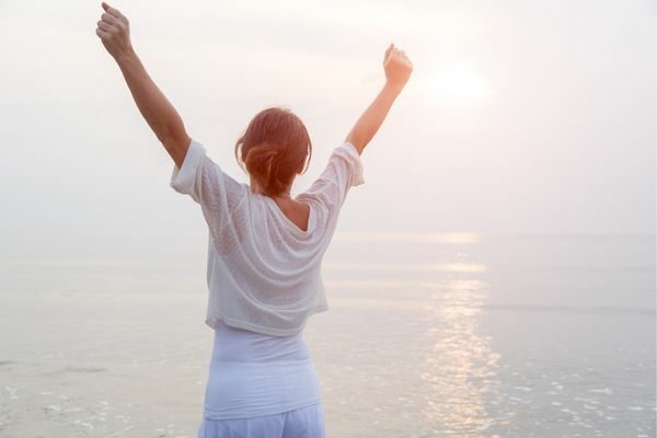 successful women habits: woman outside with arms up