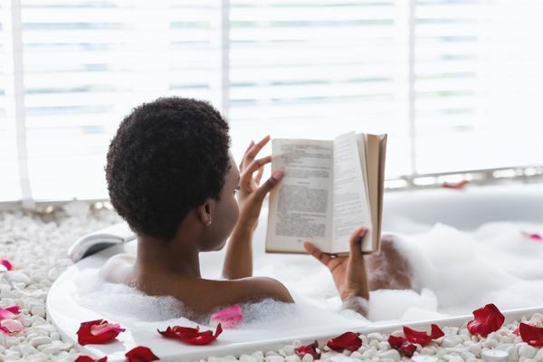 woman reading in bath; self care bingo cards challenge