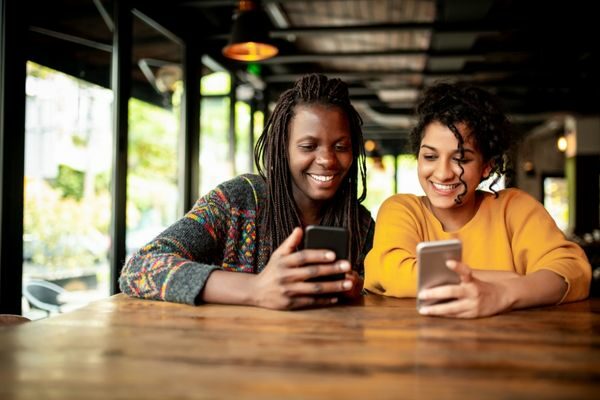 two women looking at phones; how to do a social media detox challenge break: make a digital plan from 30 days to 1 year