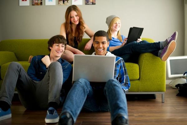 teens sitting on couch laughing on computer