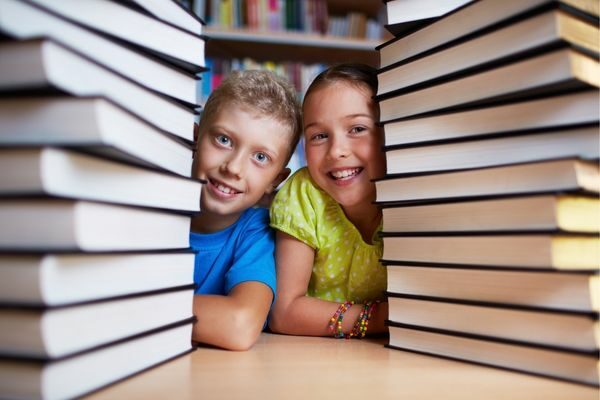 two kids in between stacks of books