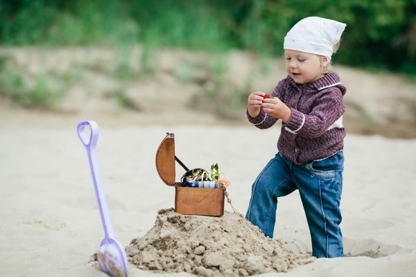 little boy dressed like a pirate with a beach treasure and shovel