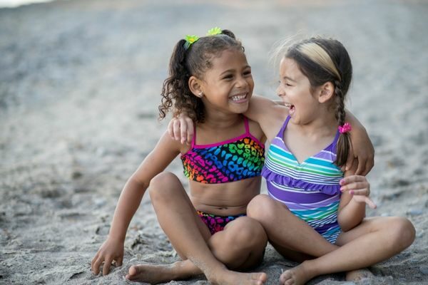 two girls sitting on the beach laughing; beach jokes