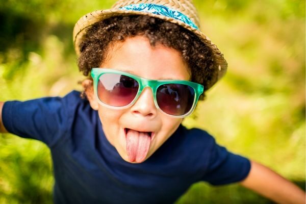 boy with hat and sunglasses sticking out tongue