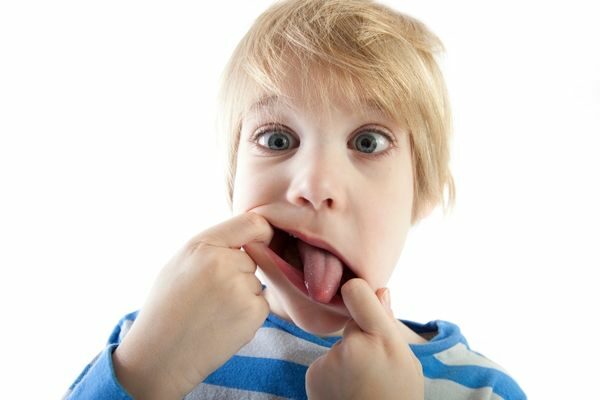 kid with hands in mouth sticking out tongue