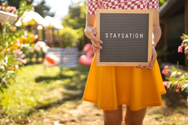 girl holding a staycation sign