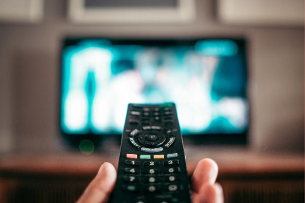 person holding a remote in front of a television