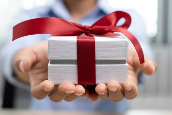 person holding out a gift with a red bow