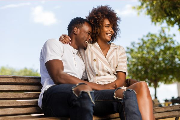 couple sitting on a bench smiling and holding hands; favorite things questions for couples