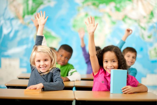 students in the classroom raising their hands