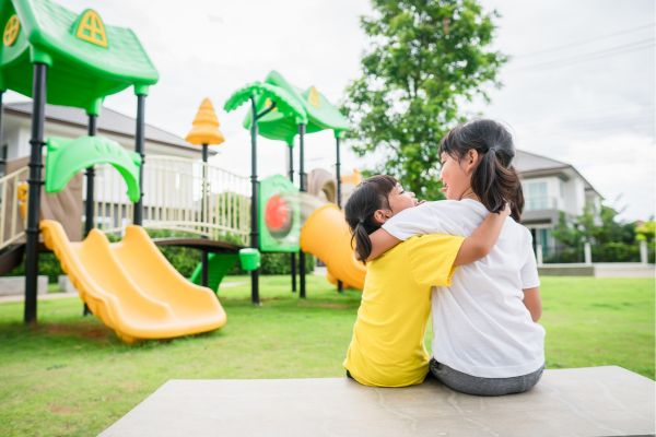 two kids hugging on a playground; encouraging words for a child and kids