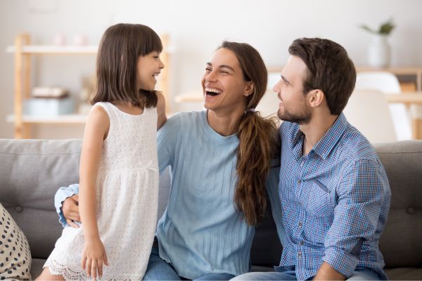 family of three smiling at each other