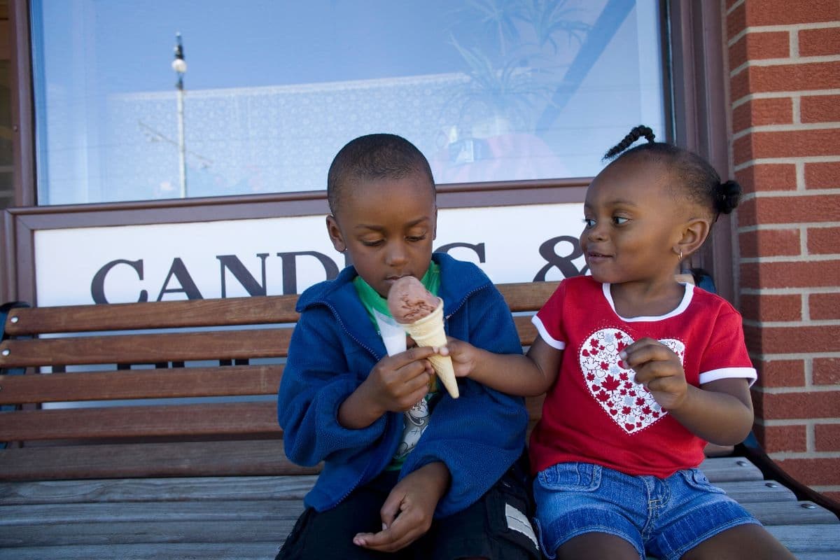 two small children sharing an ice cream cone