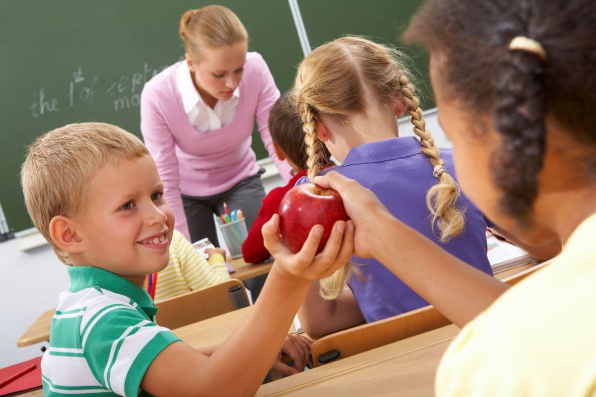 boy handing a girl an apple in class