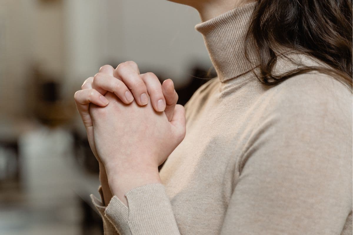 woman holding her hands together in prayer