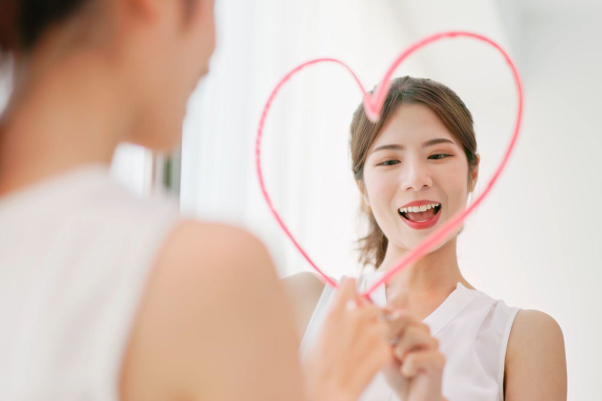 woman looking in mirror with a heart drawn; self reflection activities