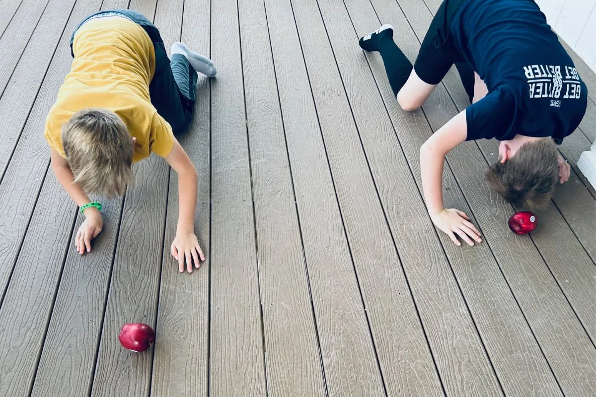 boys pushing apples with their heads